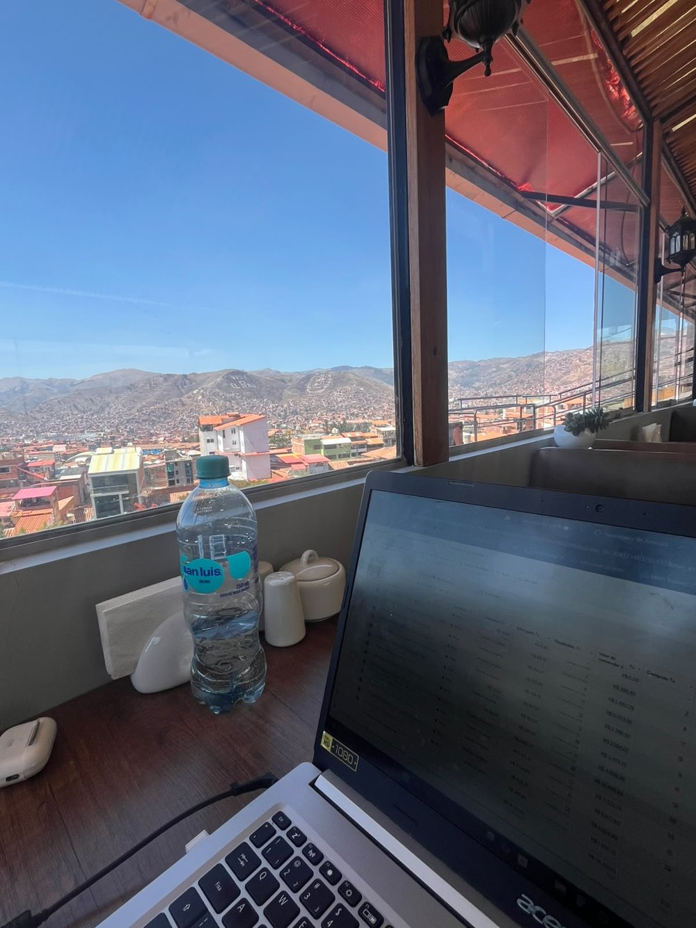 Notebook na mesa de um café, com a cidade e as montanhas ao fundo
